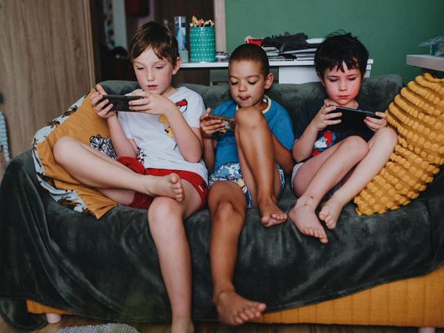 Tre gutter som ser på mobiltelefonen sin