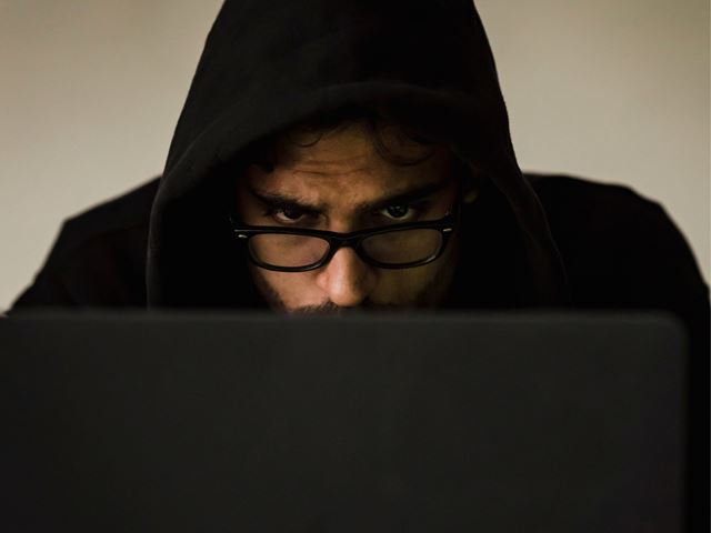 Mann i hette genser som stirrer på pc