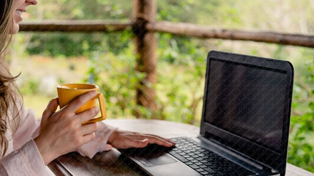 Dame med kaffekopp foran pc